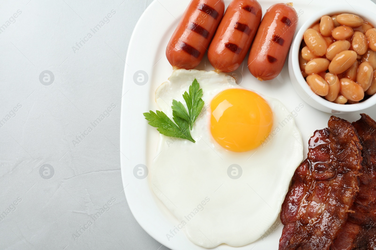 Photo of Delicious breakfast with fried egg served on light table, top view