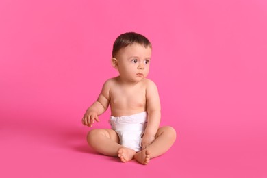 Photo of Cute baby in dry soft diaper sitting on pink background