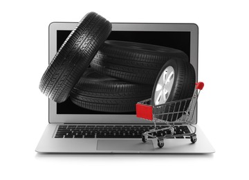 Image of Online auto store, delivery service. Modern laptop, shopping cart and car tires on white background