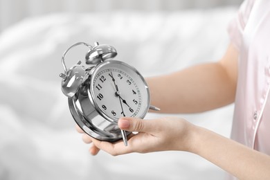 Photo of Woman with alarm clock indoors, closeup view