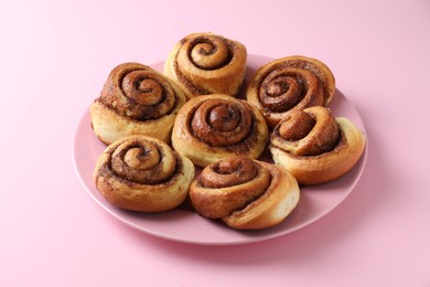 Photo of Many tasty cinnamon rolls on pink background, closeup