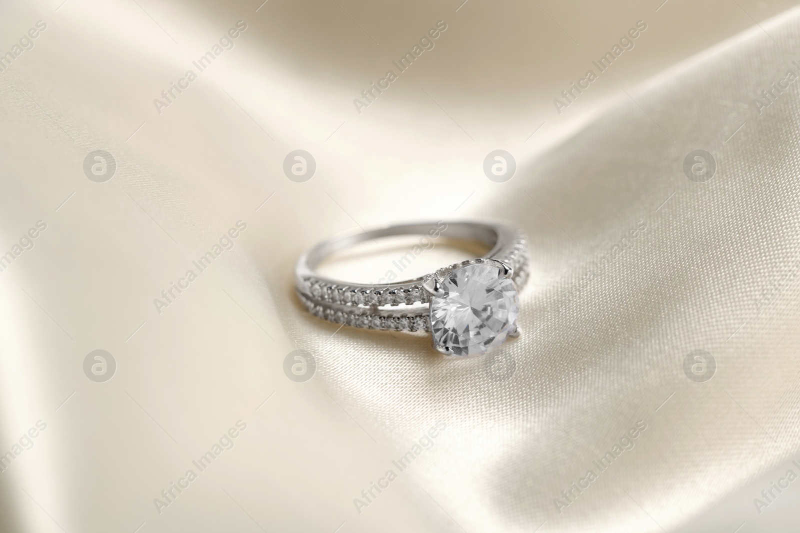 Photo of Beautiful ring with gemstones on white fabric. Luxury jewelry