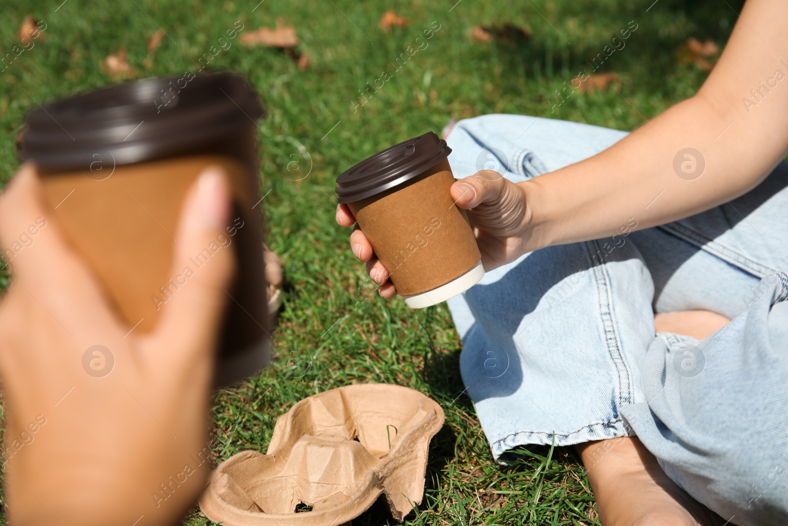 Photo of Women holding takeaway cardboard coffee cups with plastic lids outdoors, closeup