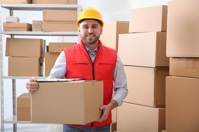 Photo of Young man with cardboard box at warehouse