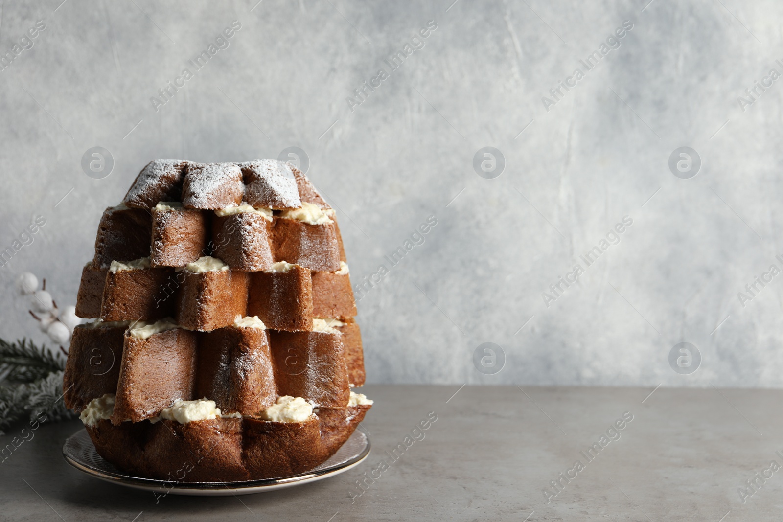 Photo of Delicious Pandoro Christmas tree cake decorated with powdered sugar on grey table. Space for text