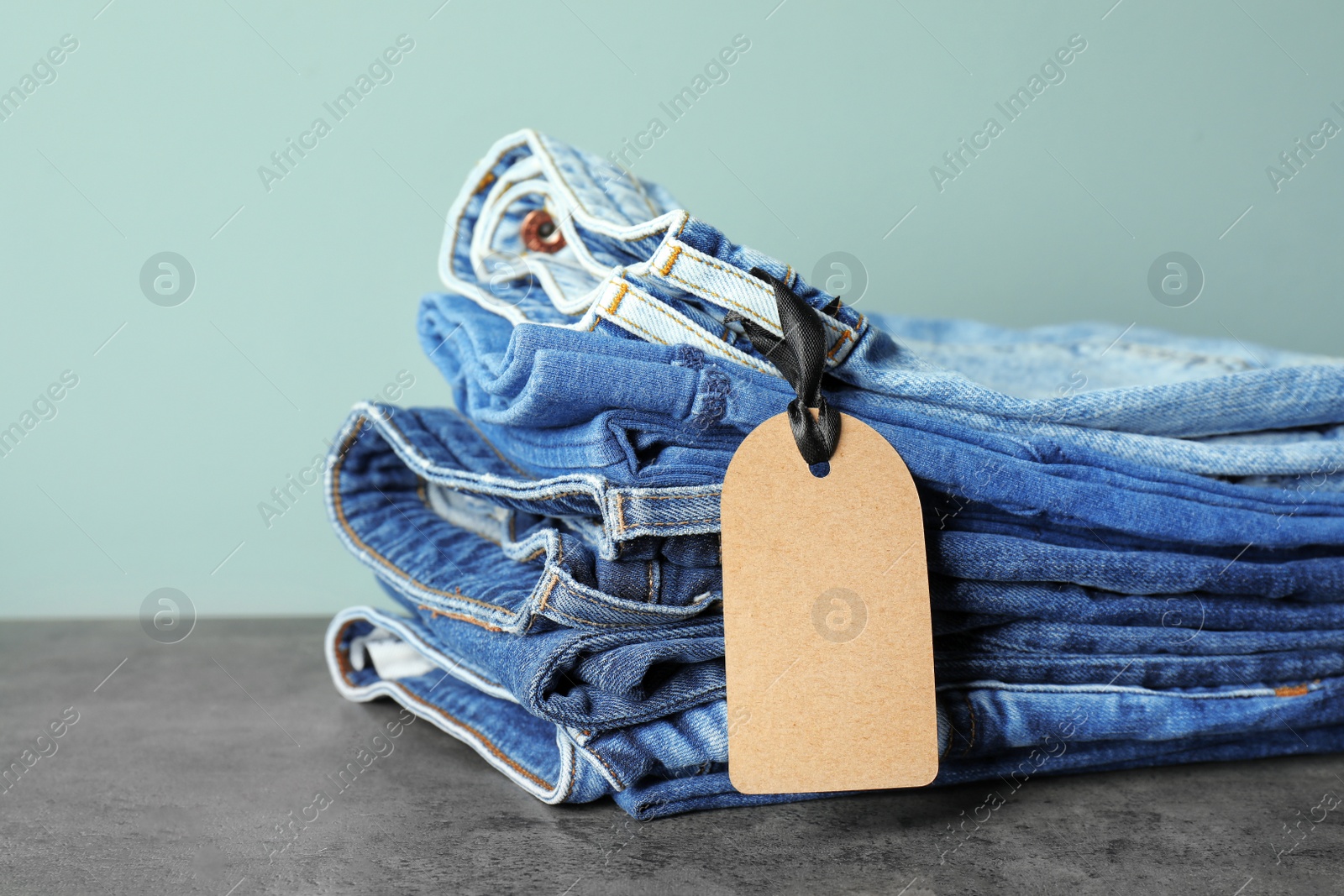 Photo of Stack of jeans on table against color background