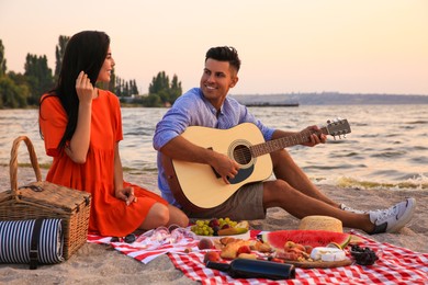 Photo of Lovely couple having picnic near river at sunset