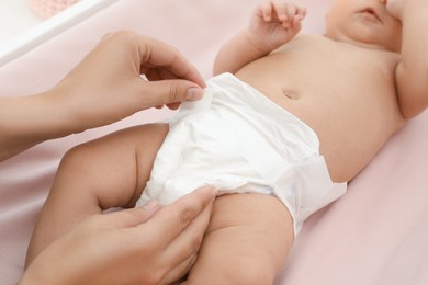 Mother changing her baby's diaper on table, closeup