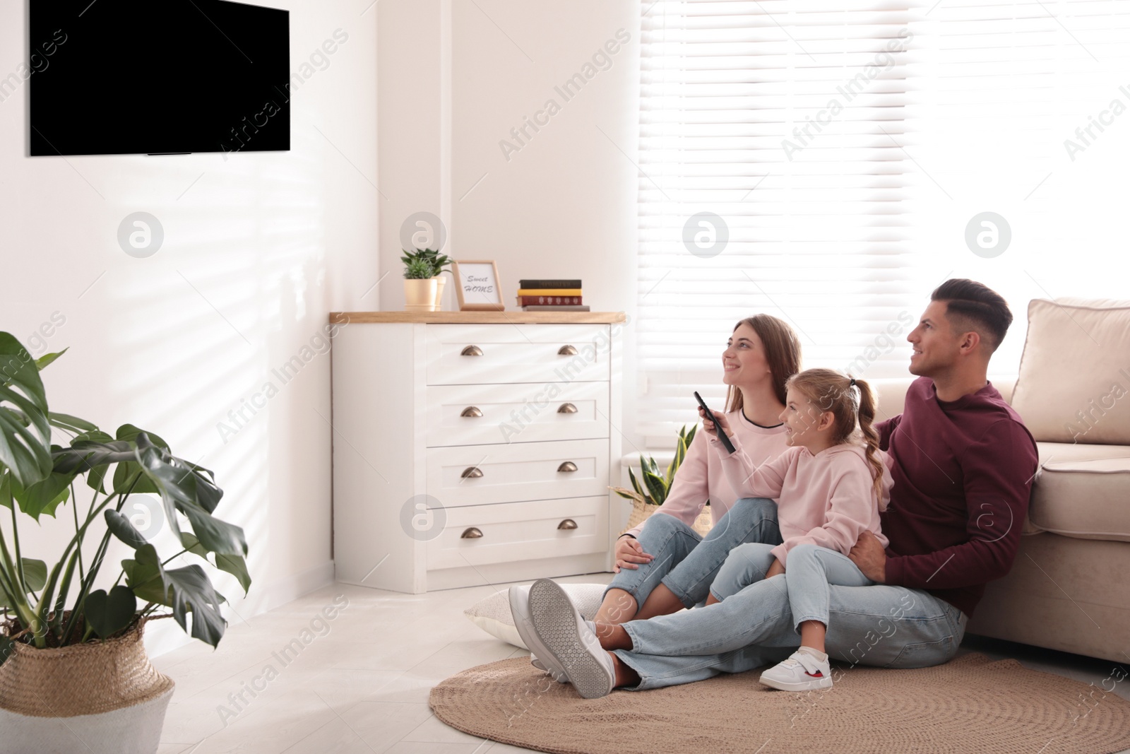 Photo of Happy family watching TV on floor at home