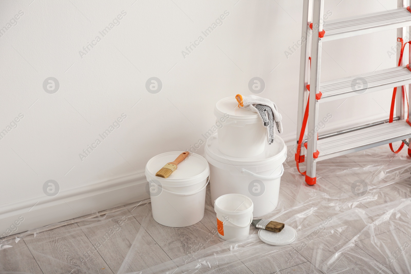 Photo of Stepladder and different tools near wall in room. Interior renovation