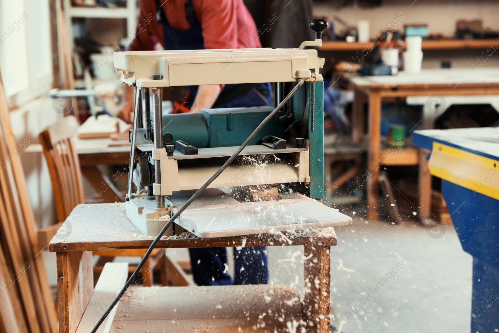 Photo of Working man using thickness planer at carpentry shop, closeup