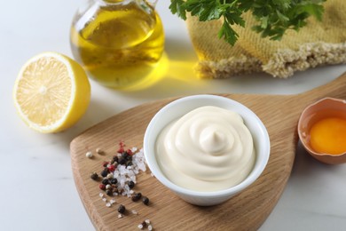 Photo of Tasty mayonnaise sauce in bowl, ingredients and spices on white table, above view