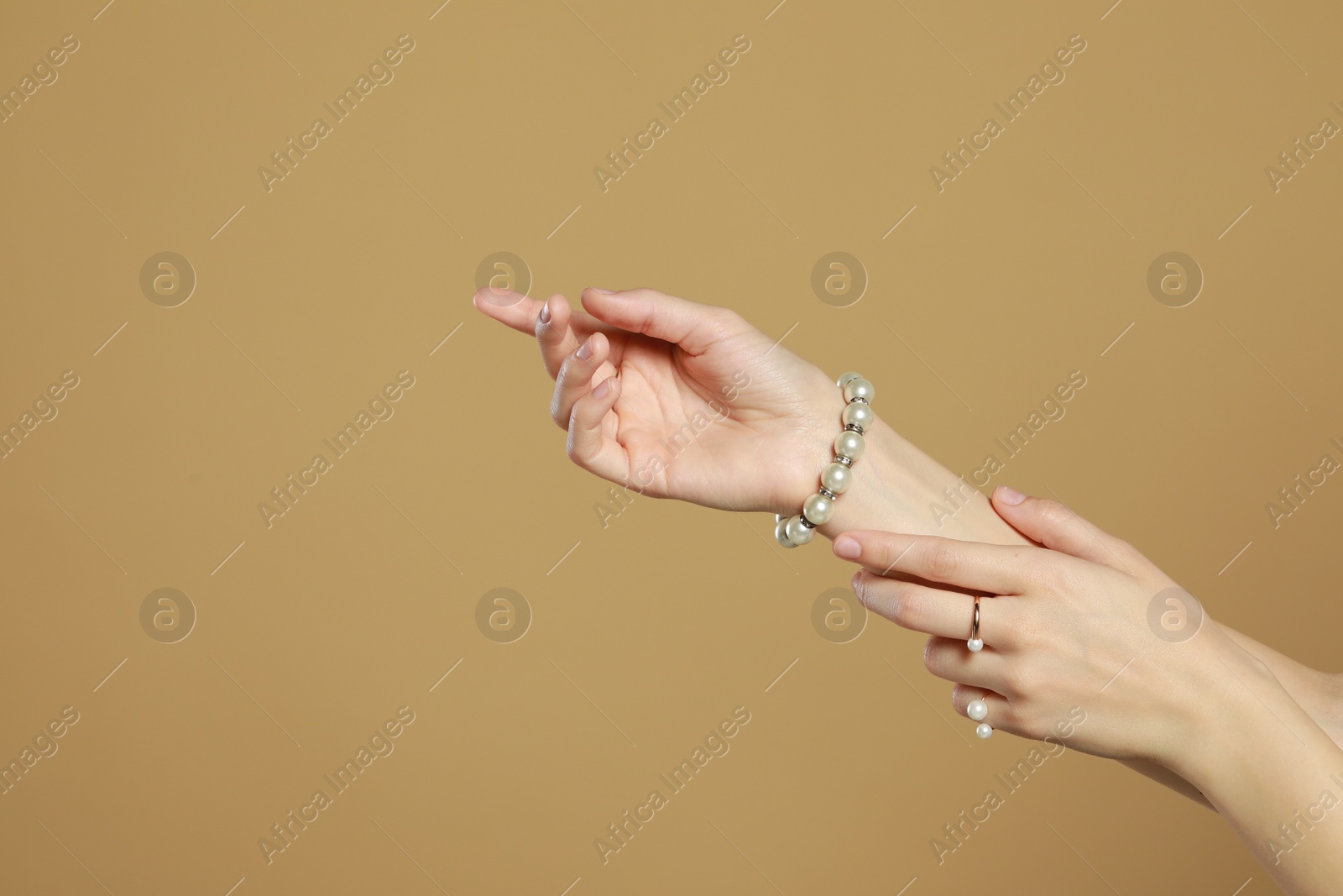 Photo of Young woman wearing elegant pearl jewelry on brown background, closeup. Space for text