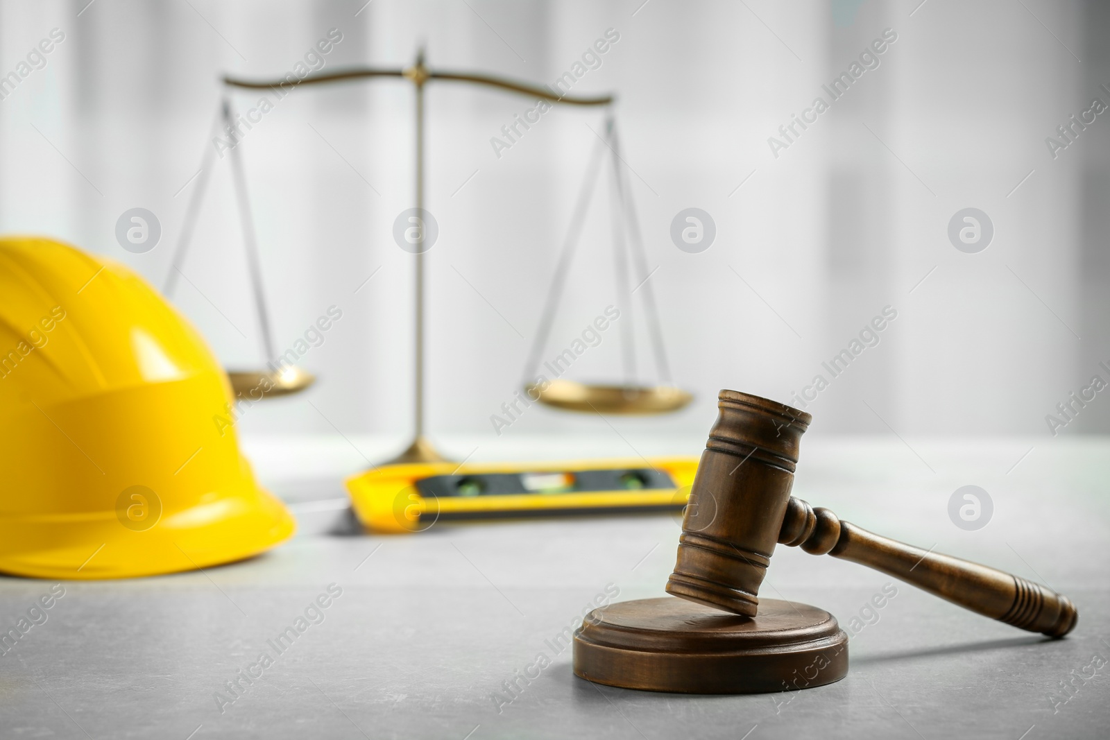 Photo of Construction and land law concepts. Judge gavel, scales of justice, level with hardhat on light grey table