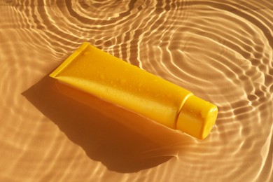 Tube with moisturizing cream in water on orange background
