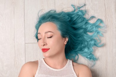 Trendy hairstyle. Young woman with colorful dyed hair on white wooden background, top view