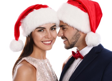 Lovely young couple in Santa hats on white background. Christmas celebration