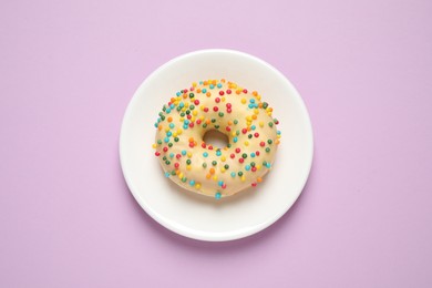 Delicious glazed donut on lilac background, top view