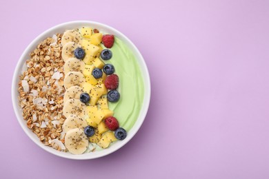 Photo of Tasty matcha smoothie bowl served with fresh fruits and oatmeal on violet background, top view with space for text. Healthy breakfast