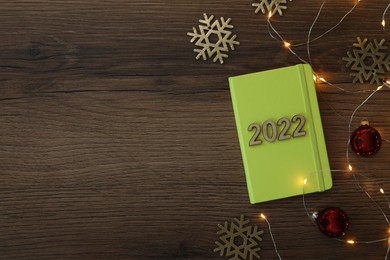 Photo of Stylish planner and Christmas decor on wooden background, flat lay with space for text. 2022 New Year aims