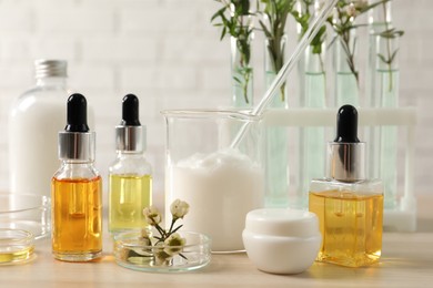 Photo of Organic cosmetic products, natural ingredients and laboratory glassware on wooden table, closeup