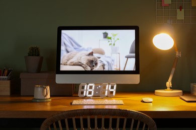 Photo of Stylish workplace with computer, houseplant and lamp near olive wall at home