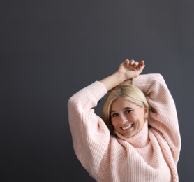 Happy woman in stylish sweater on black background. Space for text