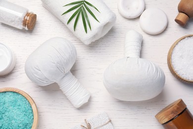 Flat lay composition of herbal bags and spa products on white wooden table