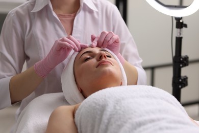 Photo of Cosmetologist making face massage to client in clinic, closeup