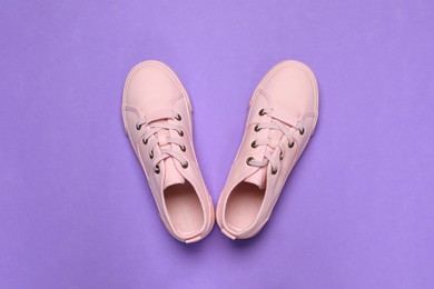 Pair of comfortable sports shoes on violet background, flat lay