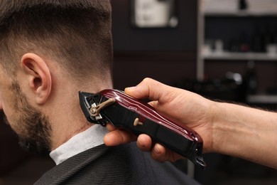 Photo of Professional hairdresser making stylish haircut in barbershop, closeup