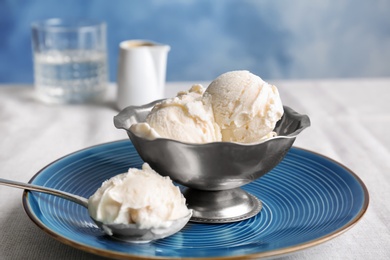 Photo of Bowl and spoon with tasty vanilla ice cream on table