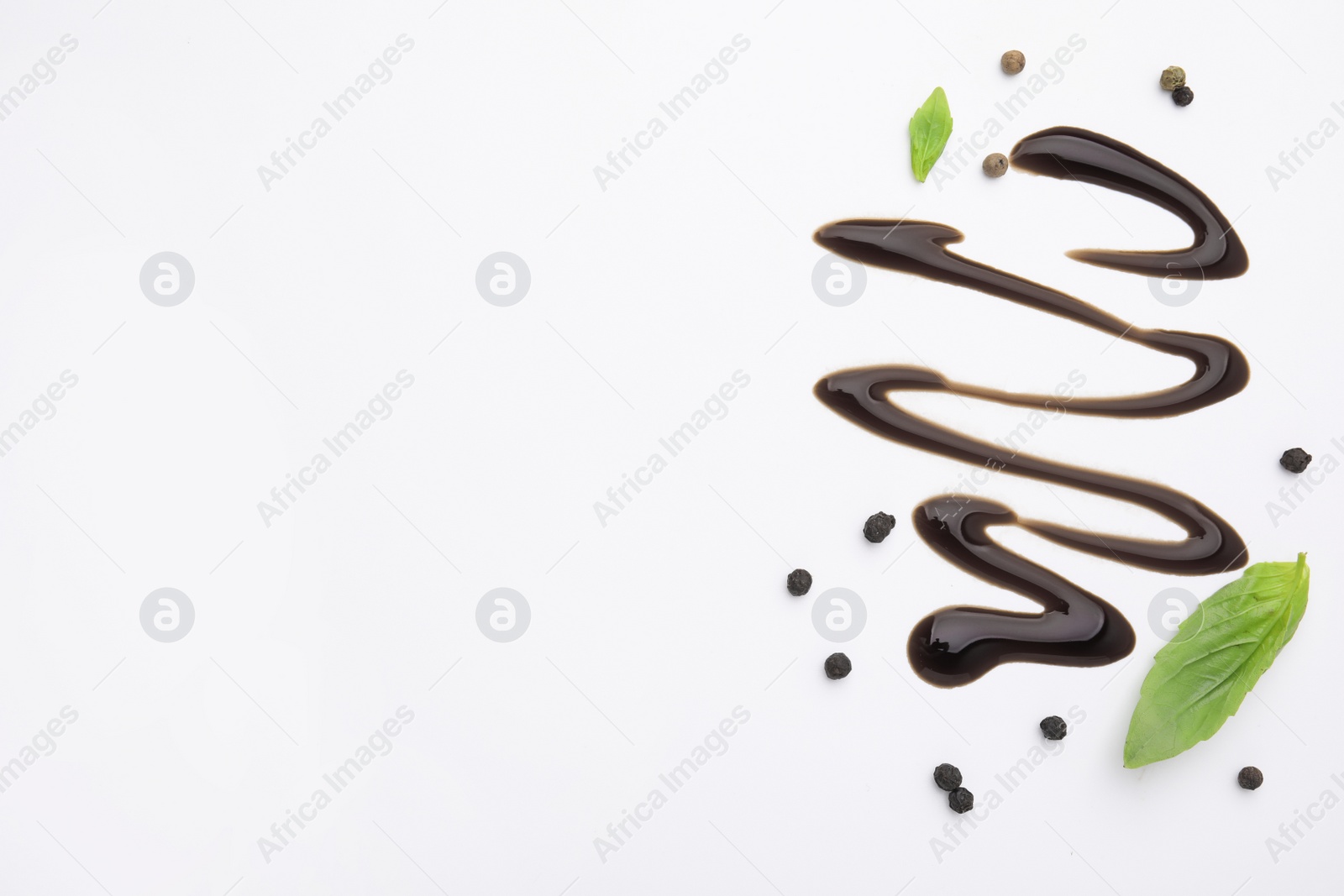 Photo of Organic balsamic vinegar, peppercorns and basil leaves on white background, flat lay. Space for text