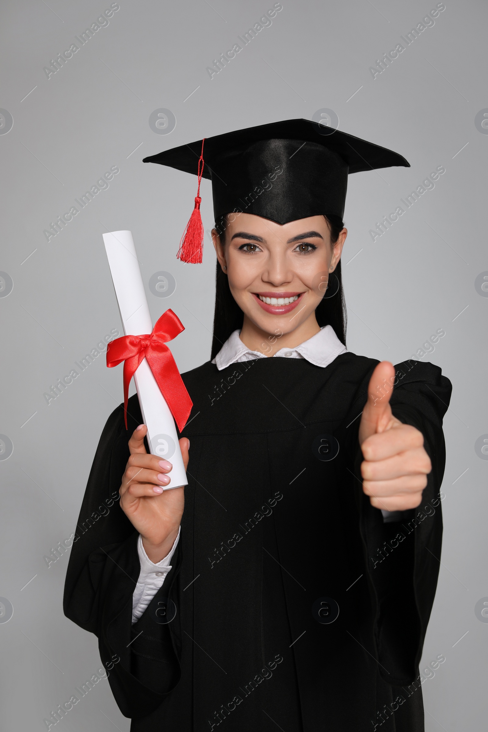 Photo of Happy student with graduation hat and diploma on grey background