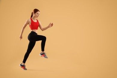Photo of Young woman in sportswear running on beige background, space for text