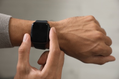 Image of Man checking stylish smart watch on grey background, closeup