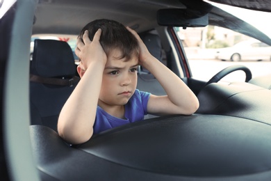 Upset little boy closed inside car. Child in danger