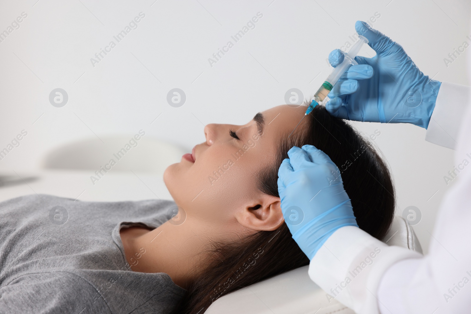 Photo of Trichologist giving injection to patient in clinic, closeup