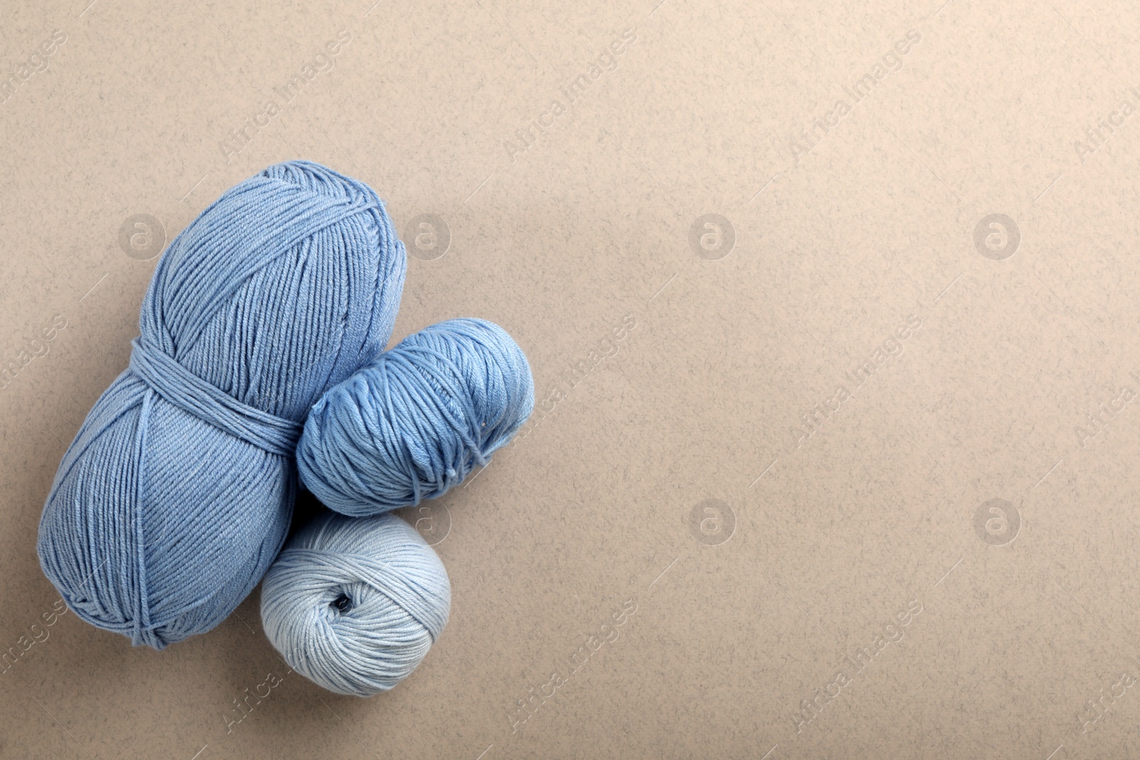 Photo of Soft woolen yarns on grey background, flat lay. Space for text