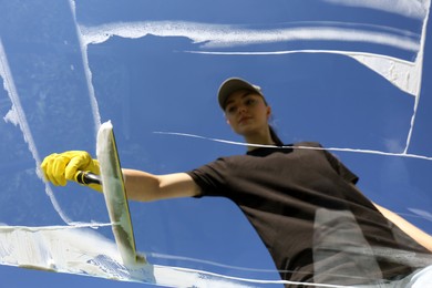 Photo of Woman cleaning glass with squeegee on sunny day