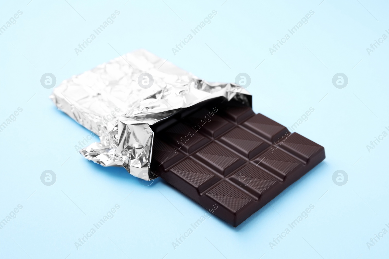 Photo of One tasty chocolate bar on light blue background