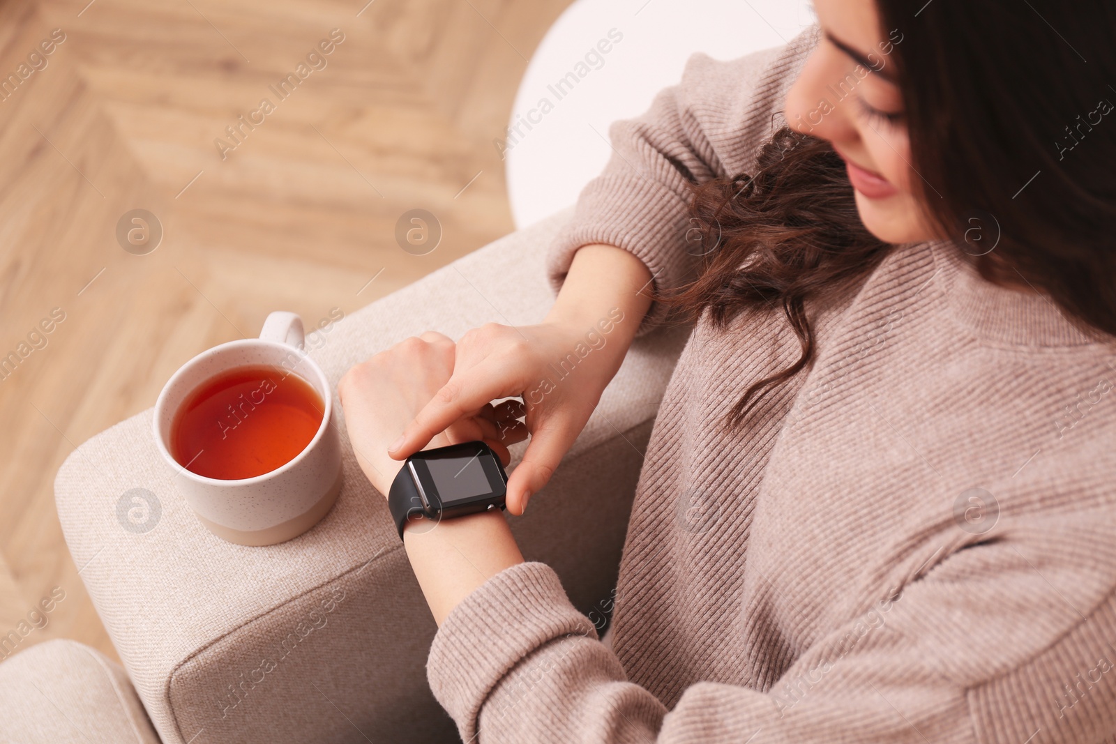 Photo of Young woman using smart watch at home