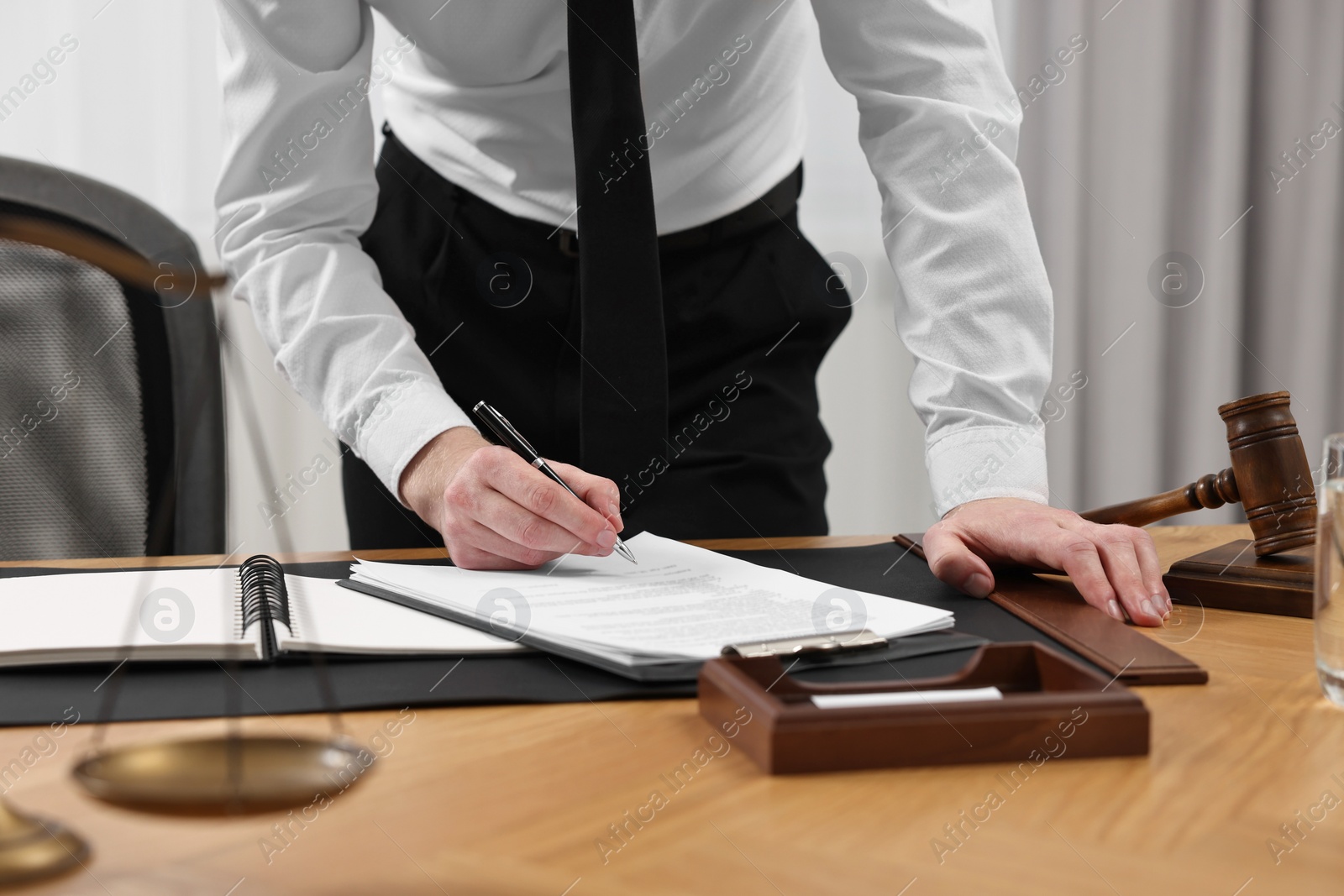 Photo of Lawyer working with documents at wooden table indoors, closeup