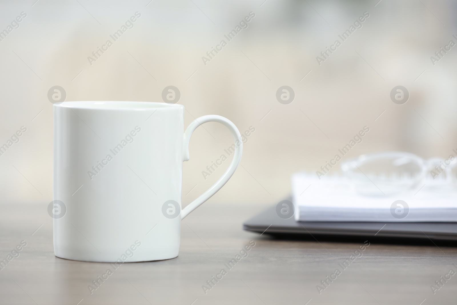 Photo of White ceramic mug on wooden table indoors. Space for text