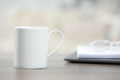 Photo of White ceramic mug on wooden table indoors. Space for text