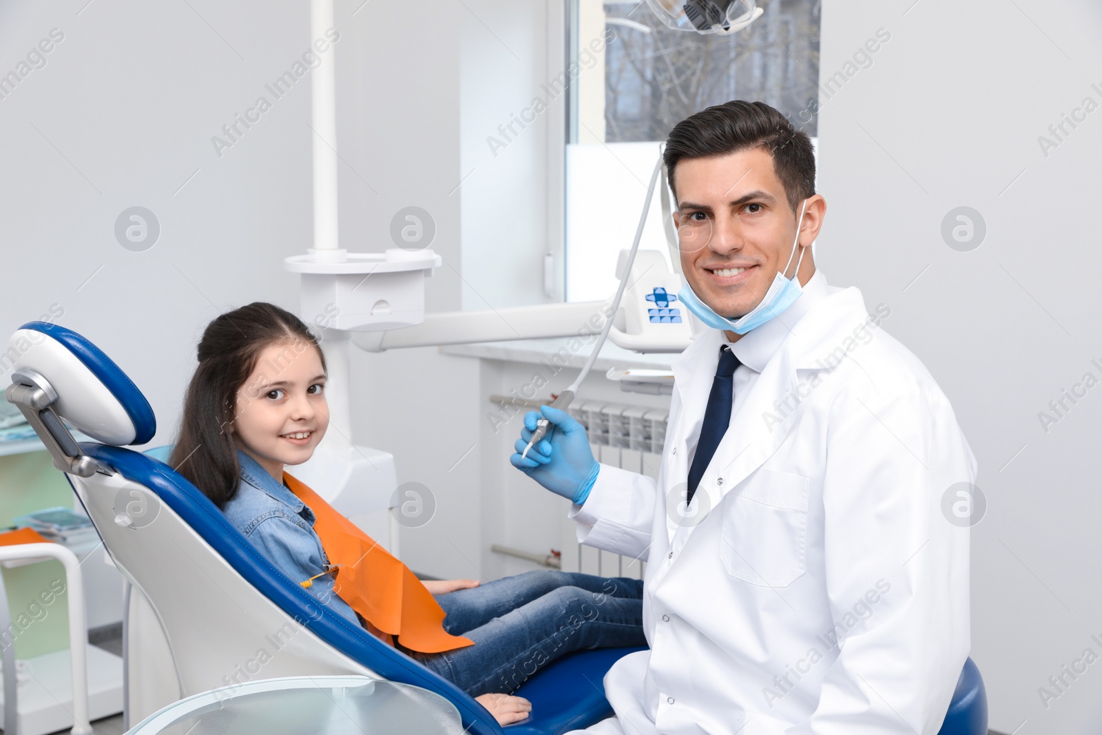 Photo of Professional dentist working with little girl in clinic