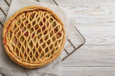 Photo of Freshly baked rhubarb pie on light wooden table, top view. Space for text