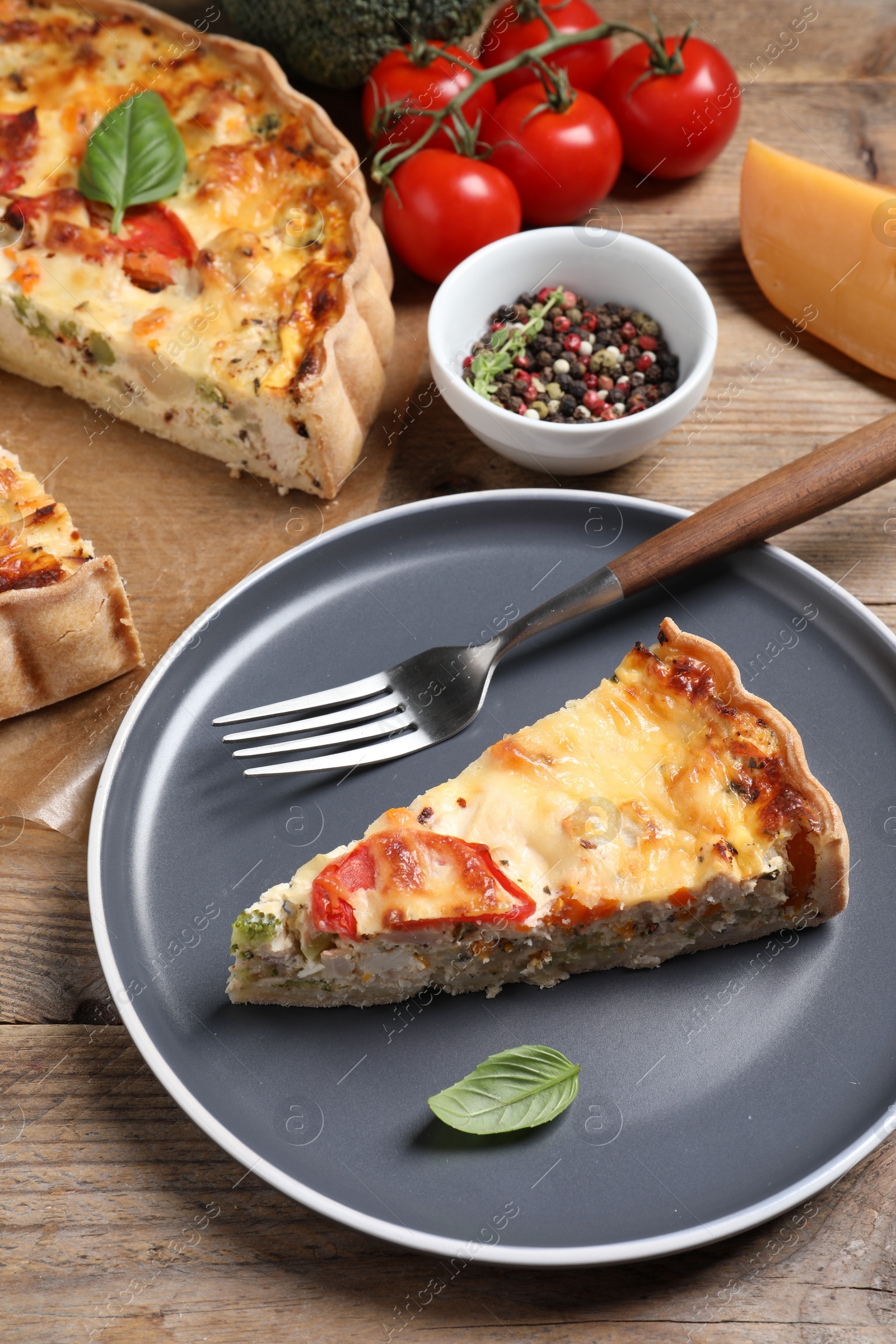 Photo of Tasty quiche with tomatoes, basil and cheese served on wooden table, above view