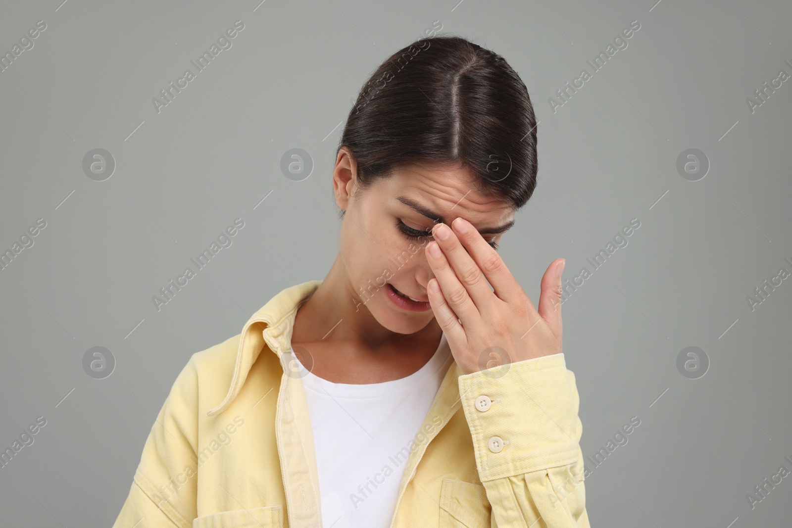 Photo of Embarrassed young woman covering face with hand on grey background