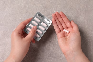Photo of Woman with blister of pills at grey table, closeup